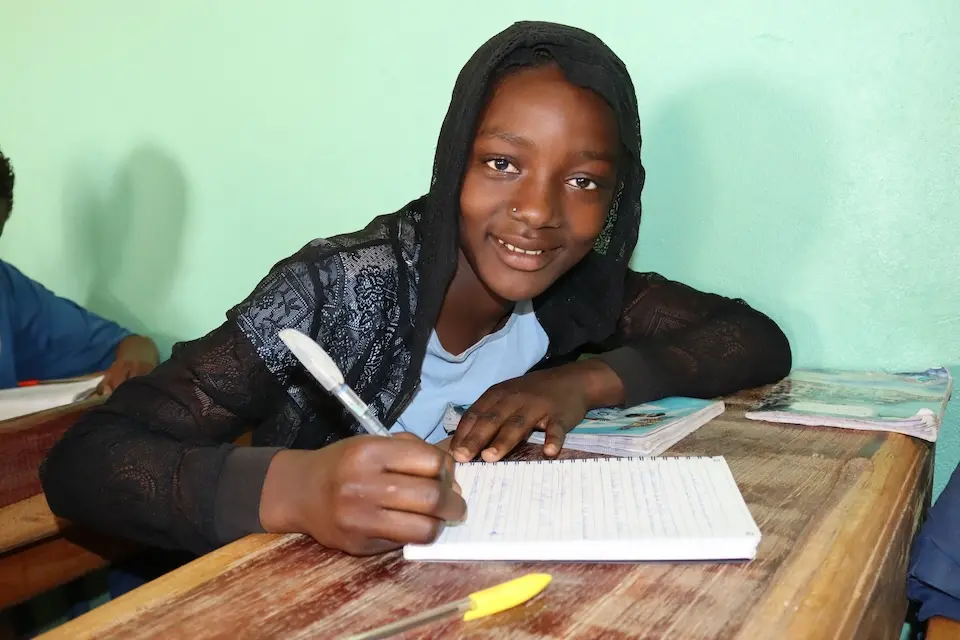 Aichatou, 12, writes in a notebook at her desk at Kongo Gamo School in Mali. 