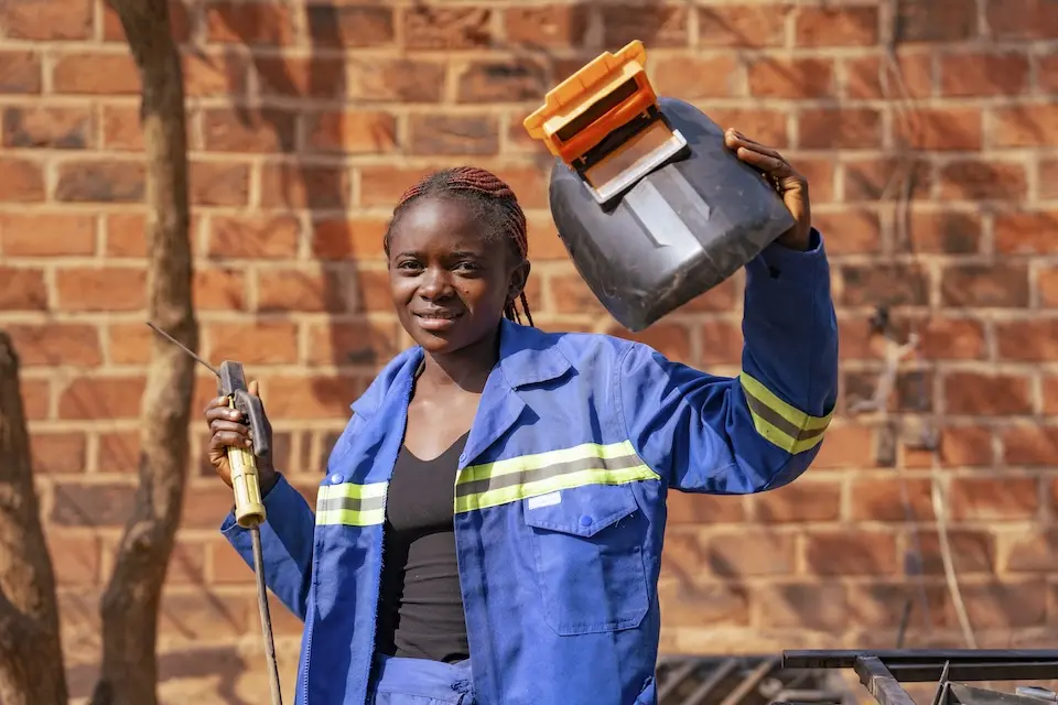Astride, 16, holds a welding mask and welding rod in an open courtyard that serves as a workshop in Tshala, Lualaba province, DR Congo.