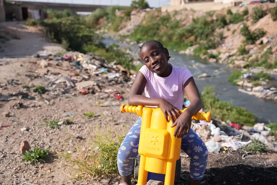 In Silvertown, near Alexandra, South Africa, 10 year-old Ompfuna sits on a yellow scooter near the banks of the polluted Juskei river.
