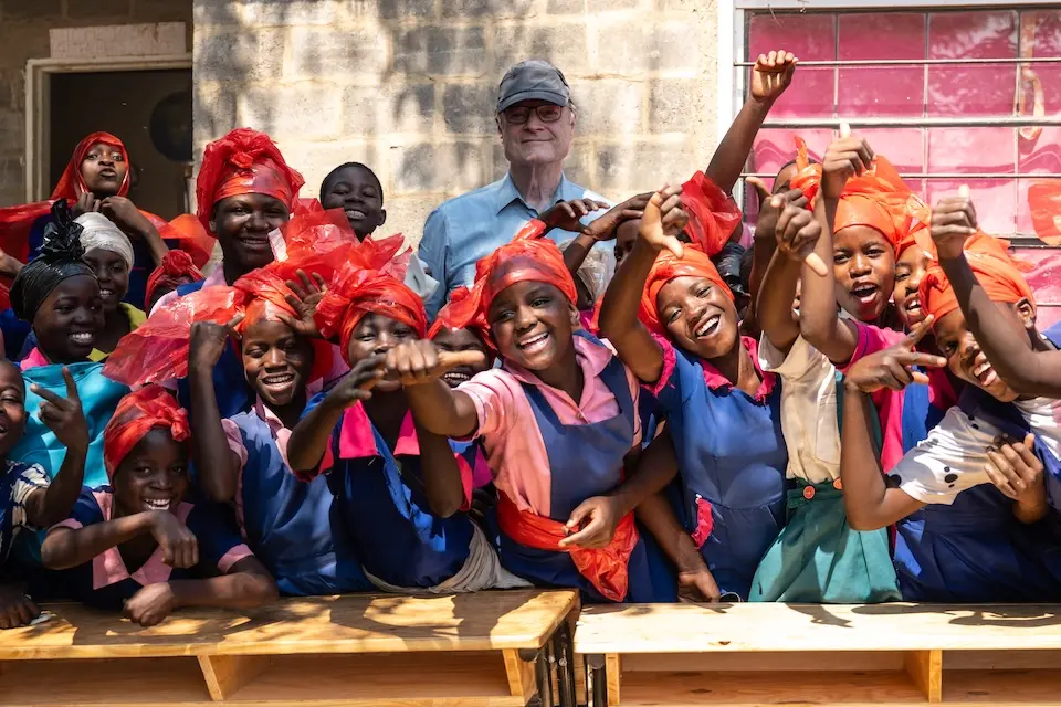 At a school in Malawi, creative students wear hats and accessories they made from plastic that covered new desks delivered by the K.I.N.D. Fund.
