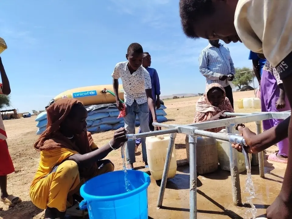 Displaced children and families from Al Fasher collect safe water delivered by UNICEF to the displacement camp in Tawila.