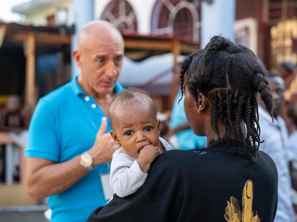 Holding her baby in her arms, a mother speaks with UNICEF Haiti's Gianluca Flamigni on Nov. 5, 2025.
