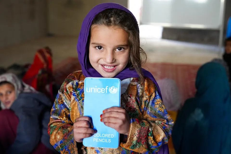 A girl in Afghanistan holds a pack of colored pencils provided by UNICEF
