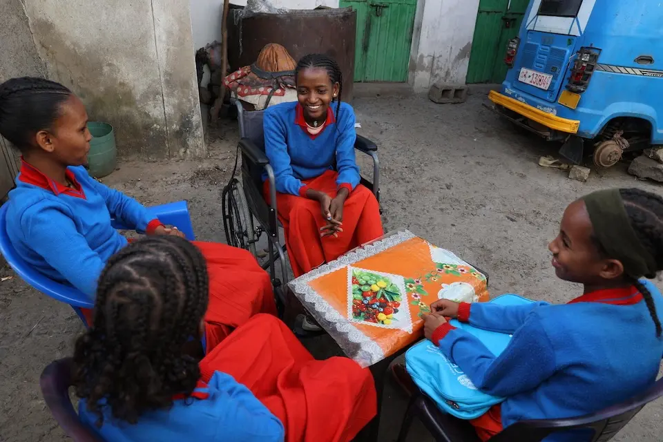 Kibra, 15, of Tigray, Ethiopia, sits in her wheelchair with three friends gathered around a table.