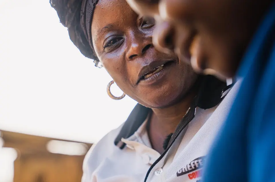 Nathalie Uyera-Malosi, mother of seven and head of a temporary foster family, sits with 15-year-old survivor of sexual violence outside their home in Bunia, Ituri province, DR Congo.
