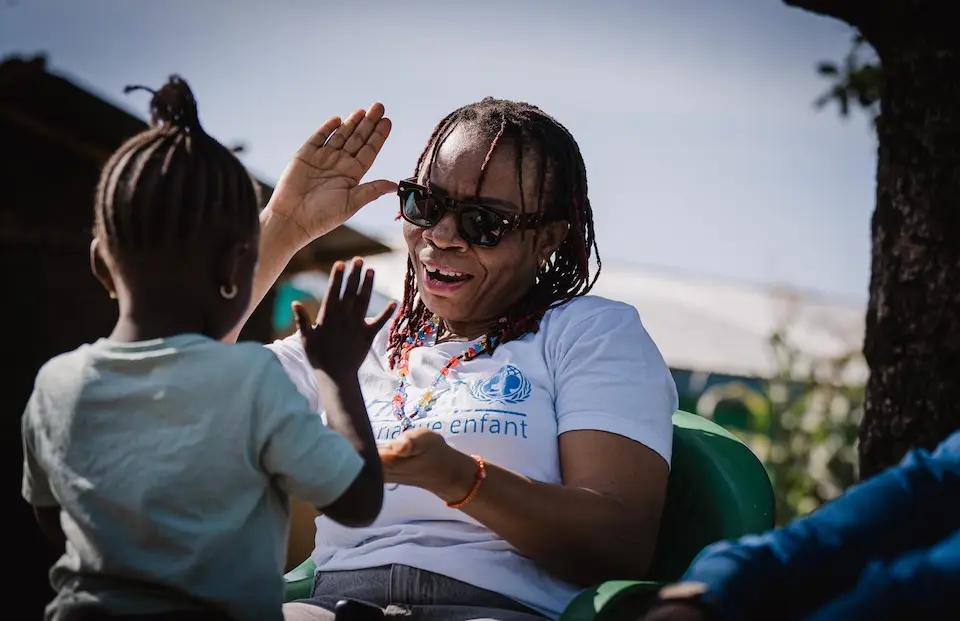 UNICEF Education Officer Wyvine Lufungulo plays with a 6-year-old survivor of sexual violence outside the girl's home in Bunia, Ituri Province, DR Congo.