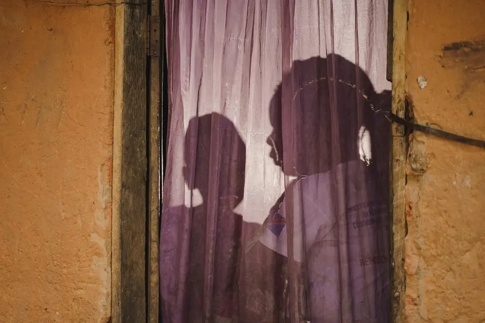A 23-year-old mother of four and daughter sit inside their home in Kananga, Kasai Central province, DR Congo.