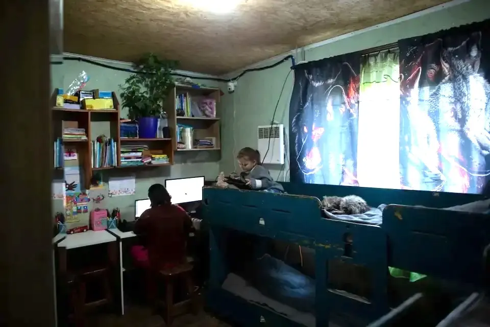 Siblings play and study in a crowded room in Kharkiv region, Ukraine. 