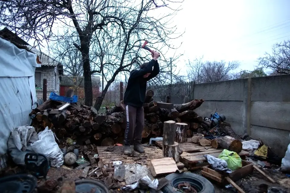 A boy chops wood to heat his family's home in Kharkiv region, Ukraine.