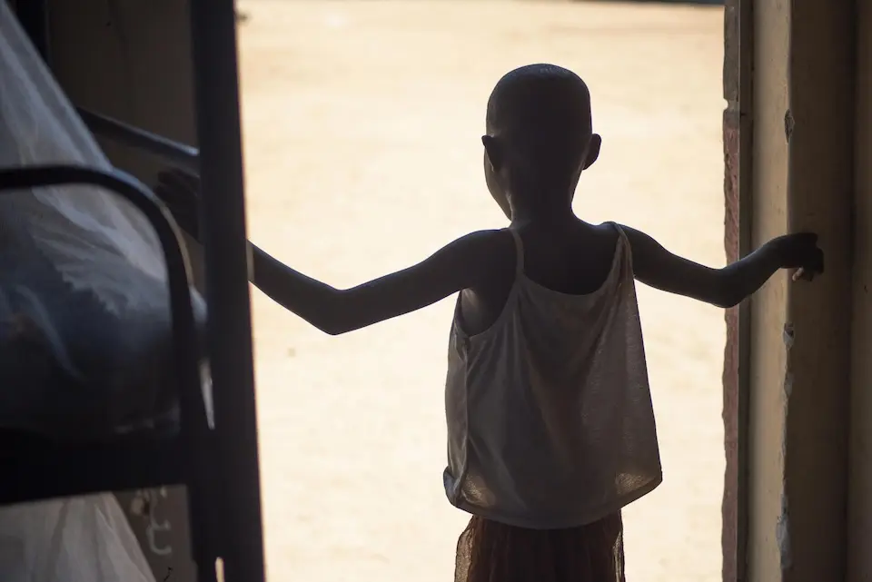 An 8-year-old protected from FGM stands in a doorway at a school in Amudat District, Uganda.