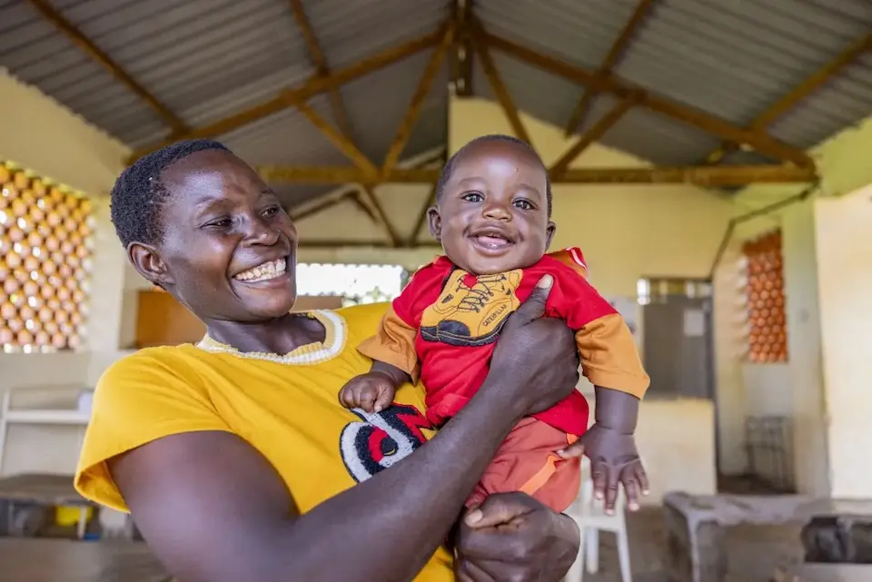 A mother poses with her baby after attending a health talk at Bumooli Health Center III, Buswale Sub-county, Uganda.