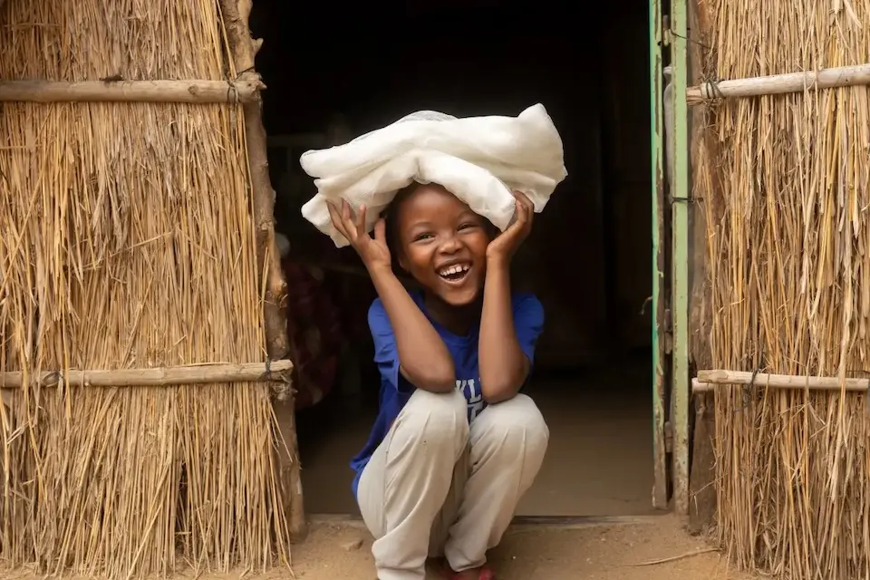 A child smiles after receiving a new bed net at her home in Arabee neighbourhood, in Damazine, Sudan.