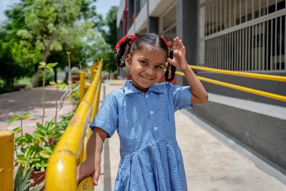 A young girl stands on an access ramp holding the railing at a school featuring inclusive infrastructure in India.