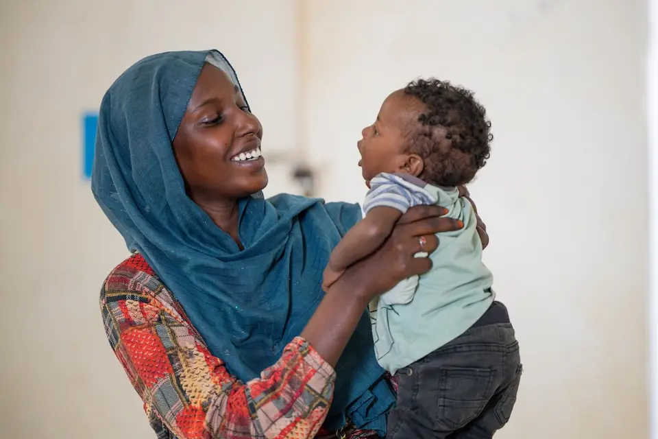 A smiling mother holds her baby, who is recovering from malnutrition with support from UNICEF, in Khartoum State, Sudan. 
