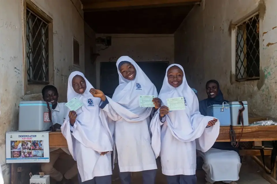 Three girls celebrate after being vaccinated at their school in Nigeria..