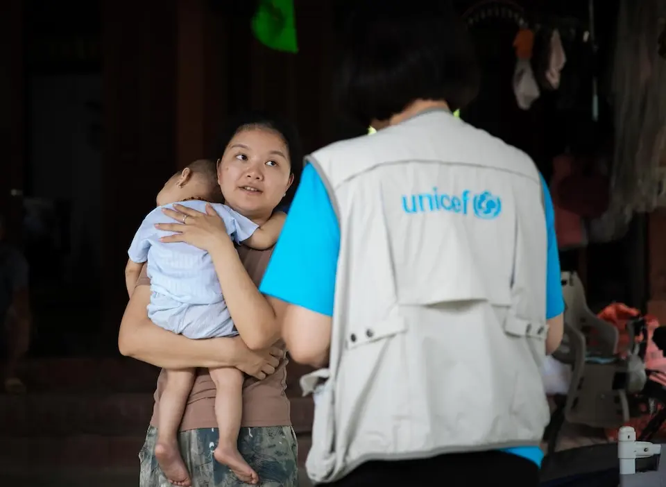 In Linh Hồ Commune, Tuyên Quang Province, Vietnam, a mother holds her 1-year-old daughter while speaking with a UNICEF staff member there to assess the child's nutrition needs.