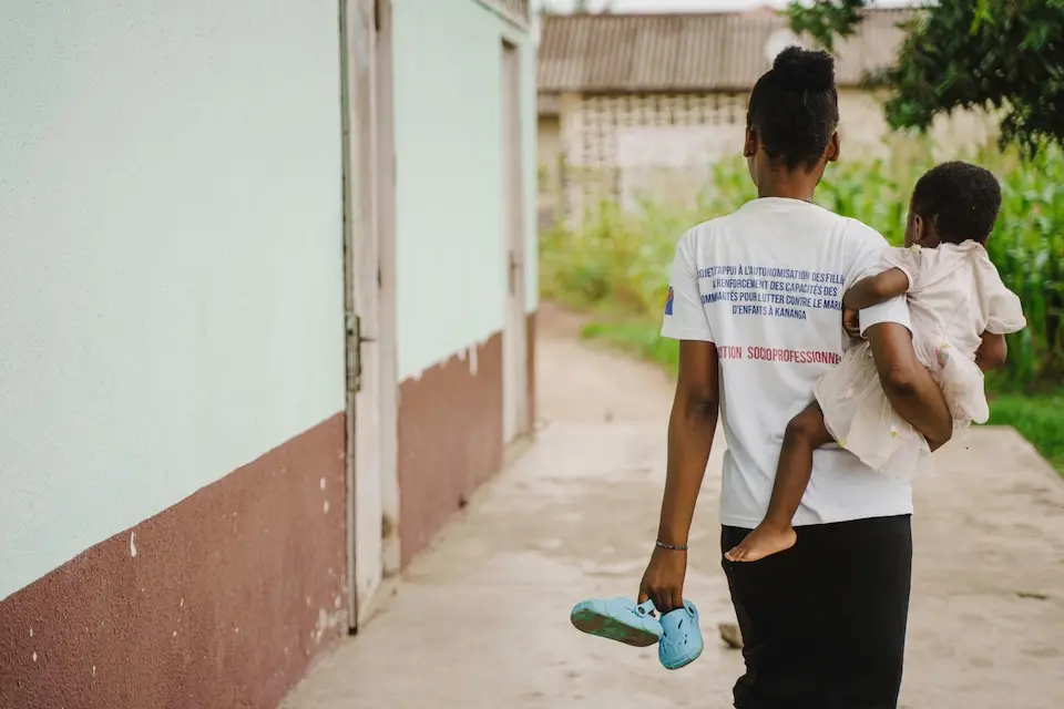 In Kananga, Kasai Central province, DR Congo, an 18-year-old old mother carries her child outside the UNICEF-supported safe space where she is enrolled in a sewing course