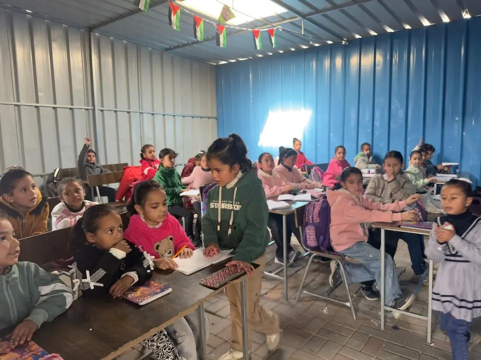 Children sit at desks in a  UNICEF-supported temporary learning center in Deir al Balah, Gaza Strip. 