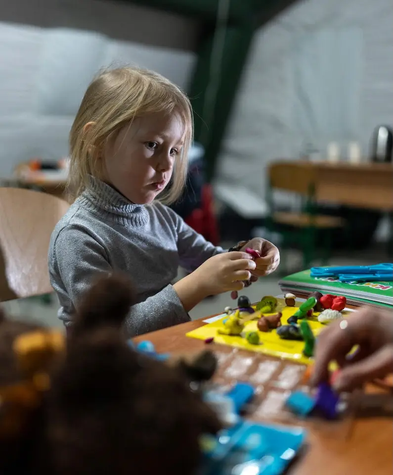 A 3-year-old girl plays with modeling clay inside a warming tent supported by UNICEF in freezing cold Ukraine.