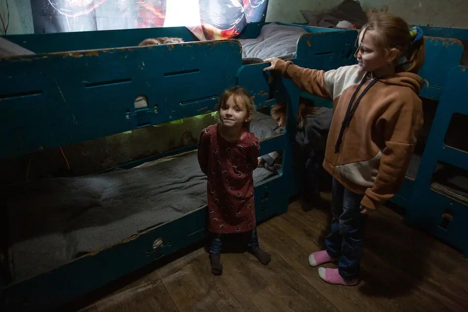 Three sisters play around tightly packed bunk beds in the room they share with their parents in Staryi Saltiv, Kharkiv region, Ukraine.