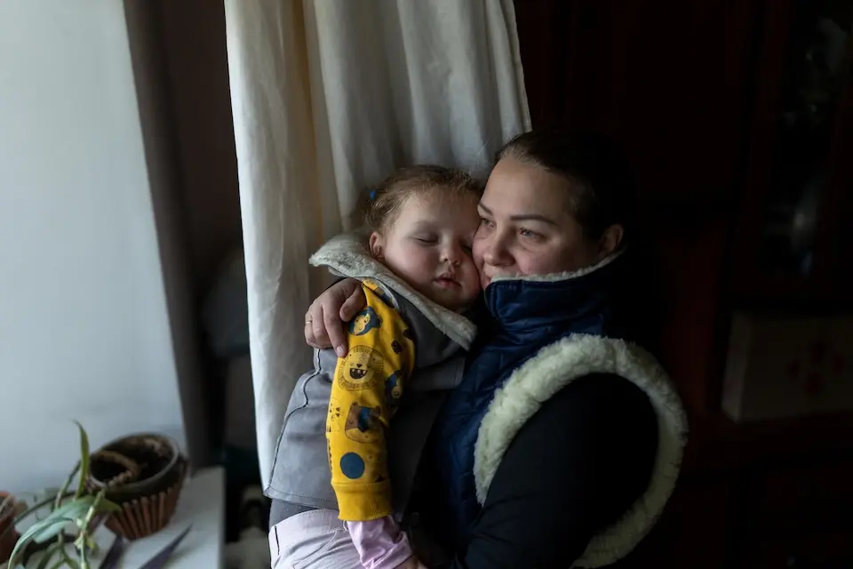 A mother holds her 3-year-old daughter close to keep her warm inside their unheated apartment in Kyiv, Ukraine.