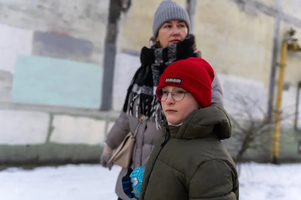 An 8-year-old boy and his mother outside their apartment building in Kyiv, Ukraine, where they live in the cold and the dark most days.