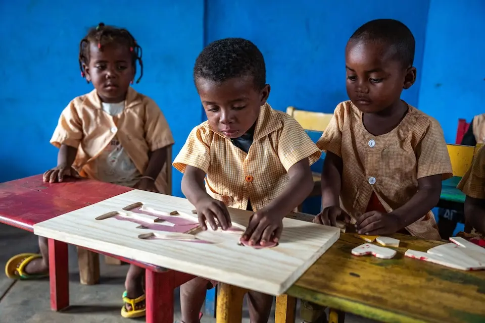 Three students work together to solve a human body puzzle at a UNICEF-supported school in Madagascar