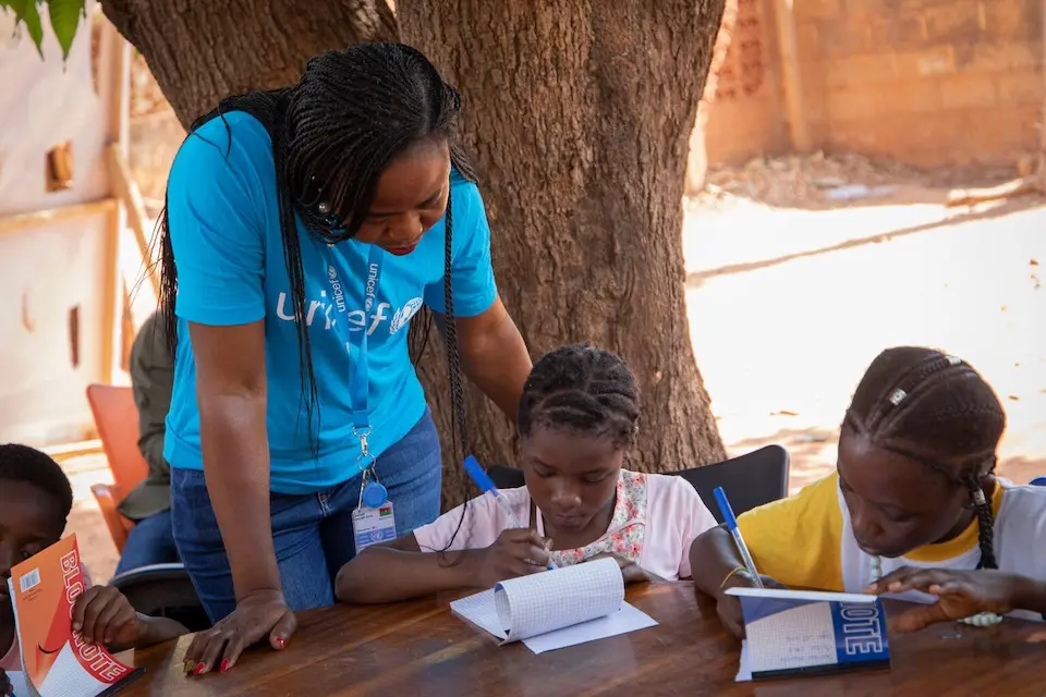 A UNICEF advocacy officer helps children at a Poems for Peace poetry writing session in Burkina Faso.