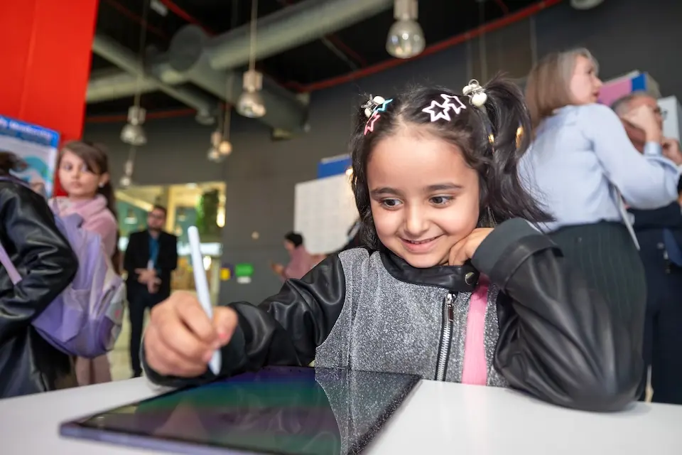 A young girl draws on a computer tablet as part of a World Children's Day event in Jordan in 2024.