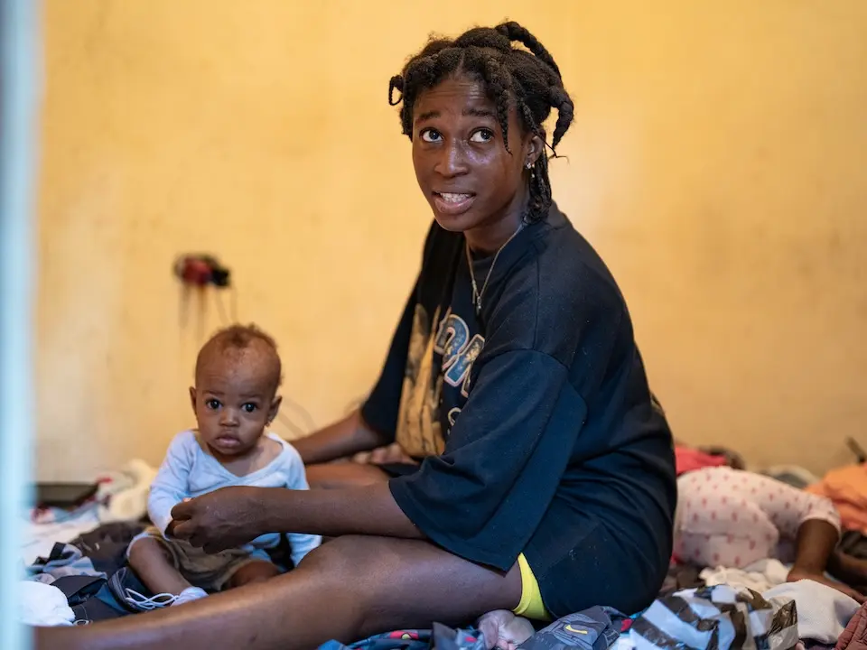 A mother and her infant daughter inside a shelter they share with other Haitian families displaced by Hurricane Melissa.