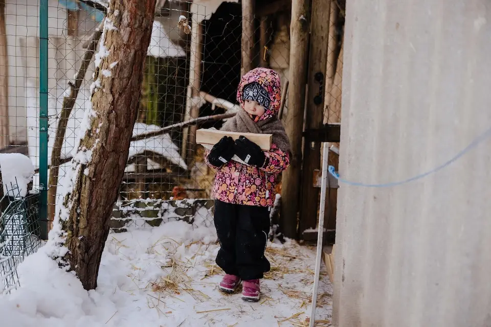 In Mykolaivka, Kyiv region, Ukraine, 4-year-old Alika carries firewood from a shed to help light a stove inside her family's house. 