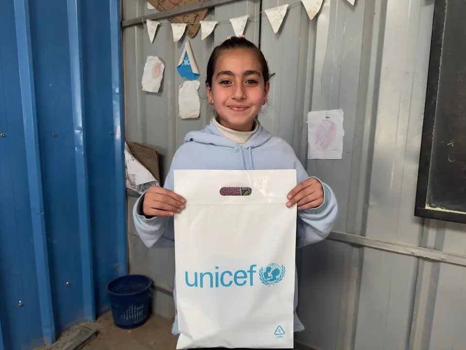 A child holds a bag of school supplies distributed by UNICEF in Deir al-Balah, Gaza Strip. 