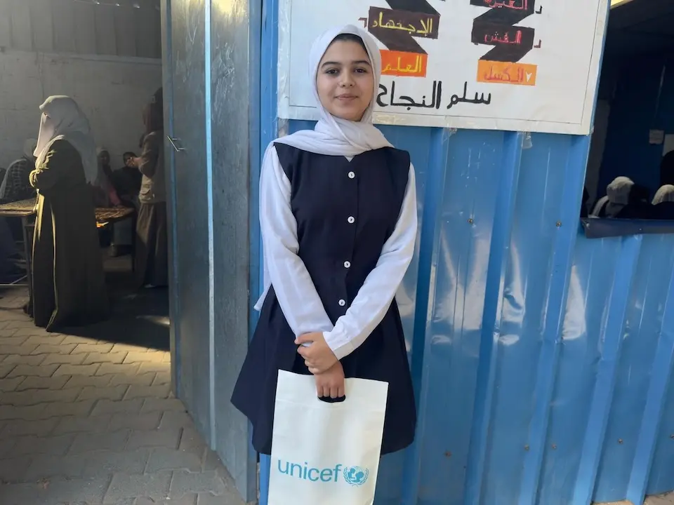 A student holds a bag of school supplies in a UNICEF-supported temporary learning space in Deir al-Balah, Gaza.
