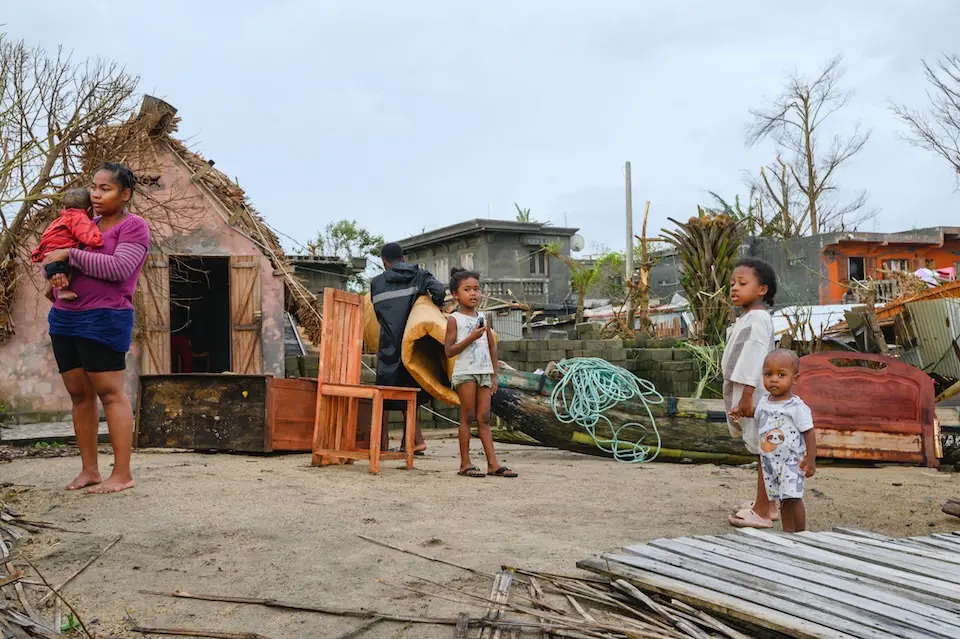 In Madagascar, a mother and four young children stand outside their cyclone-damaged home