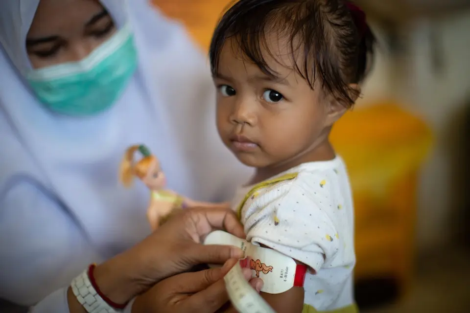 A nurse measures a 2-year-old girl during a medical examination in Indonesia. 