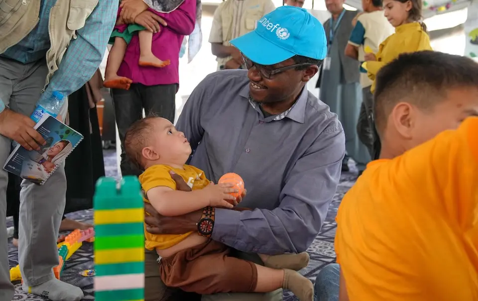  Dr. Tajudeen Oyewale, UNICEF Representative in Afghanistan, sits with a child on his lap in a child-friendly space set up by UNICEF in the border reception center at Islam Qala in western Afghanistan near Herat.