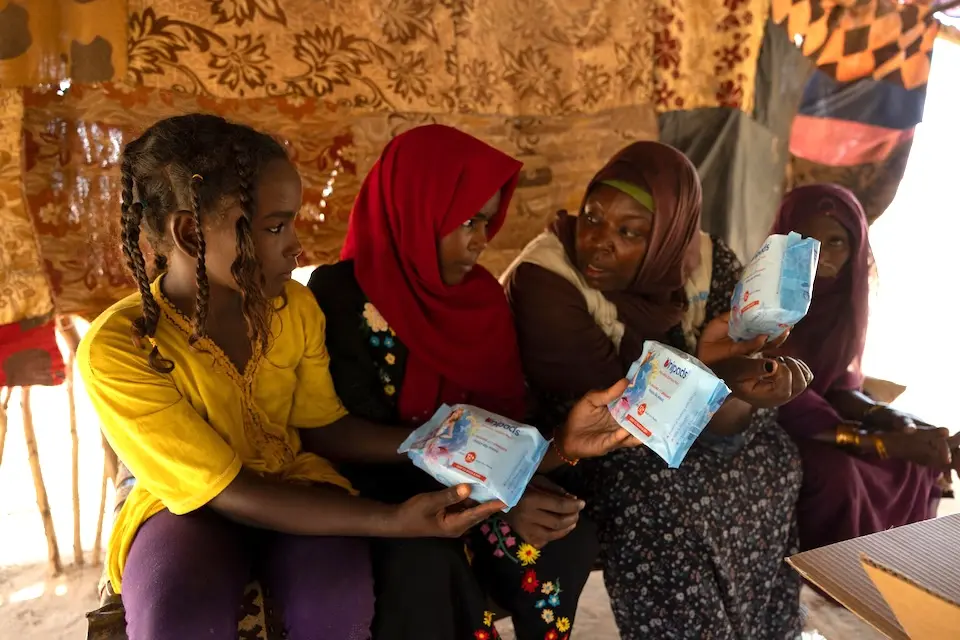 A UNICEF WASH Specialist hands over dignity kits to girls in Aldamer, River Nile State, Sudan..