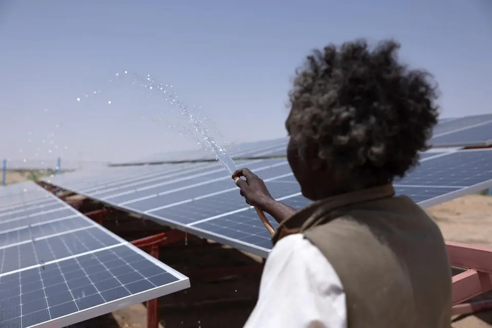 A water user committee member and caretaker cleans the solar panels of the new solarized water facility installed with UNICEF support in Aldamer, River Nile State, Sudan.