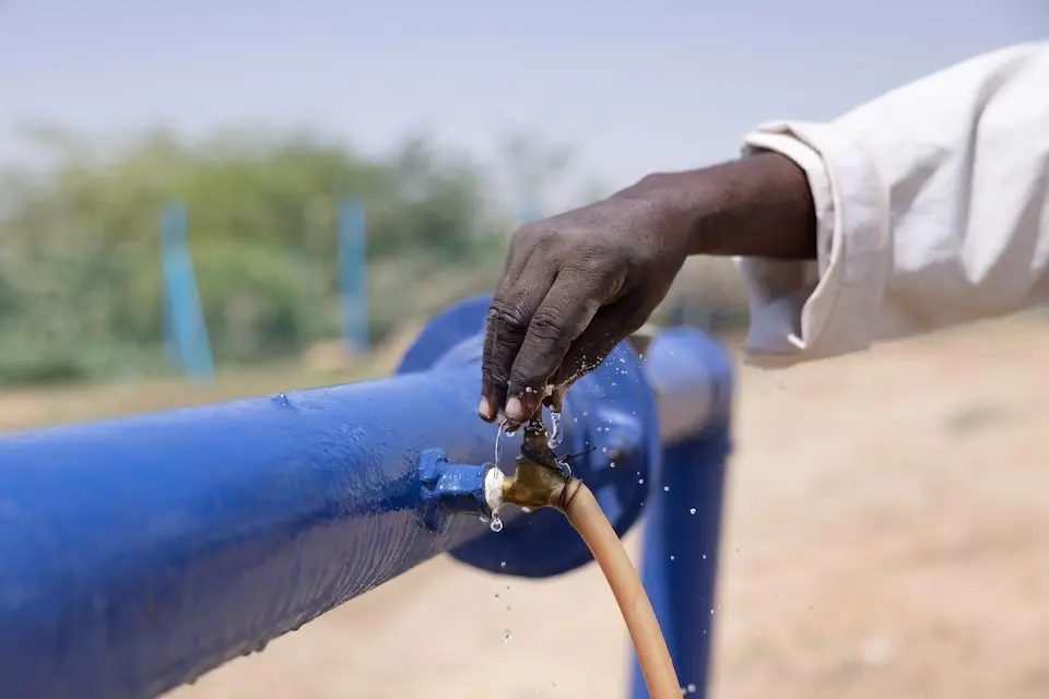 A man turns on a tap at a new solarized water facility installed with support from UNICEF in River Nile State, Sudan.
