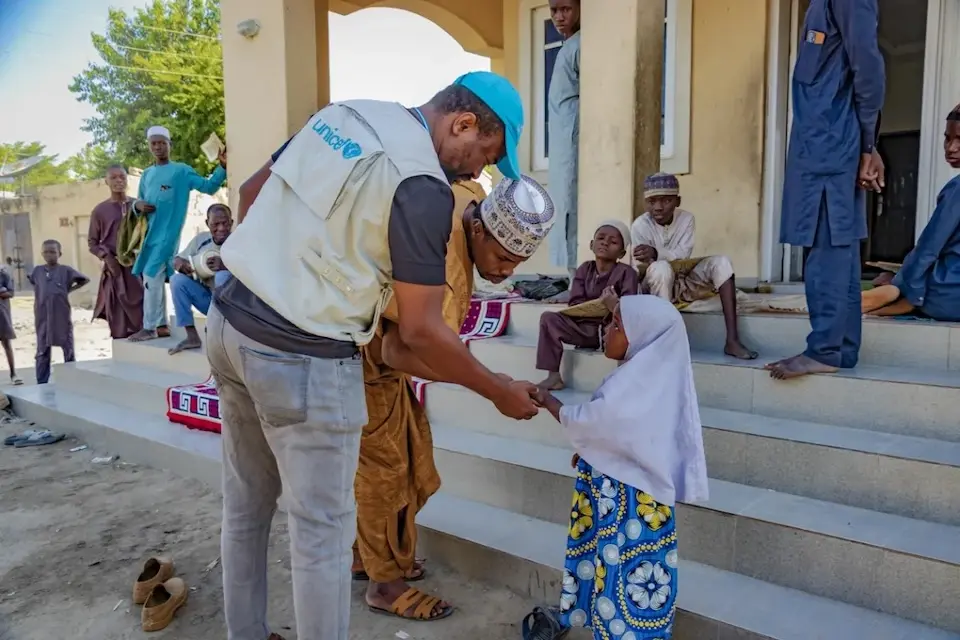 A UNICEF immunization officer checks the marked finger of a child in Nigeria to verify she has been vaccinated.