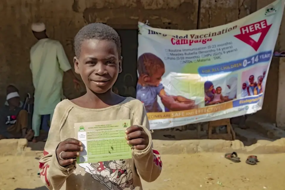 A child is Nigeria holds up his vaccination card.