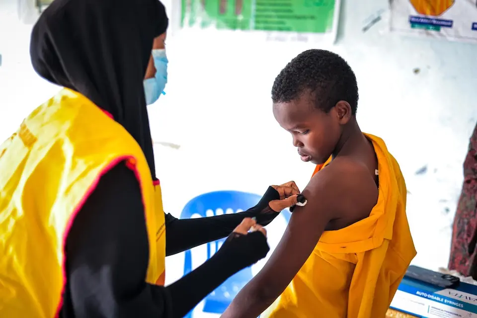 A trained vaccinator administers a routine immunization to a student in Somalia, providing protection against preventable diseases. 