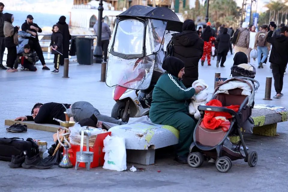 A mother feeds her baby in a public space crowded with people and their belongings in Beirut, Lebanon on March 5, 2026. 