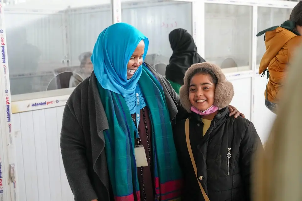 On March 10, 2026, UNICEF's Fathia Omar Hassan stands with a 15-year-old Afghan girl who has just returned from Iran with her family via the Islam Qala border crossing.