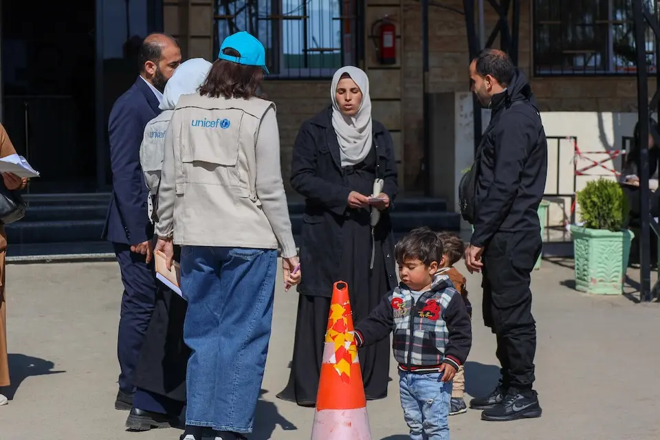 UNICEF staff speak with a Syrian mother and her children at the Joussieh border crossing on March 10, 2026.