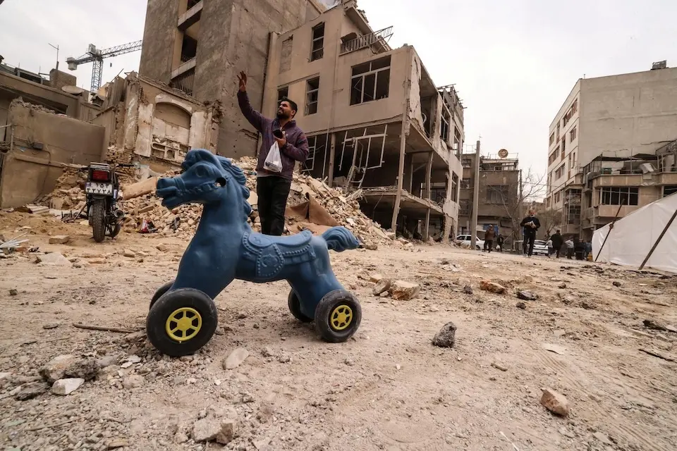 Ένας Ιρανός άνδρας κάνει χειρονομίες καθώς στέκεται κοντά σε κατεστραμμένα σπίτια μετά από στρατιωτική επίθεση στην Τεχεράνη στις 15 Μαρτίου 2026.