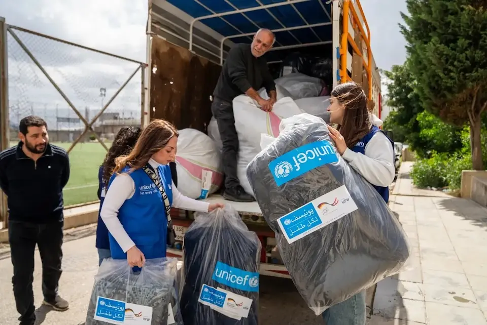 Humanitarian workers unload a truck full of winter clothing and blankets for children and families displaced by war in Lebanon. 
