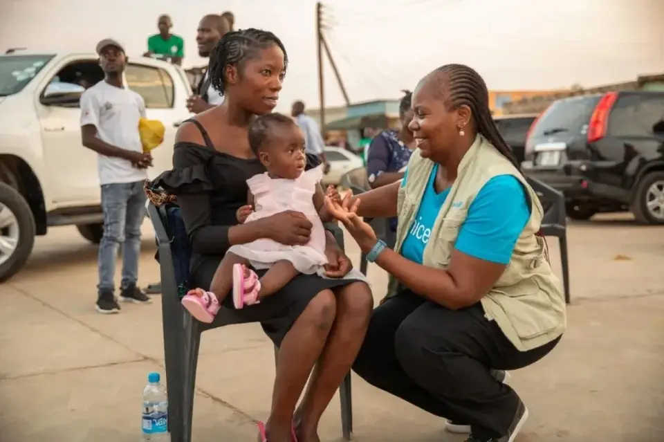 A UNICEF staff member supports a mother as her child received a malaria vaccination in Mansa district, Zambia.