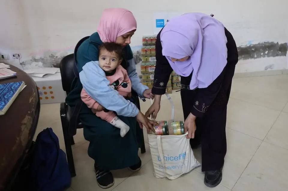 A mother picks up food for her baby at a UNICEF nutrition center