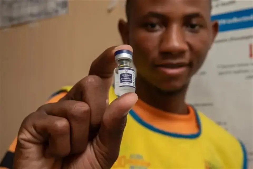 A volunteer nurse in Zambia holds a vial containing a dose of the malaria vaccine.